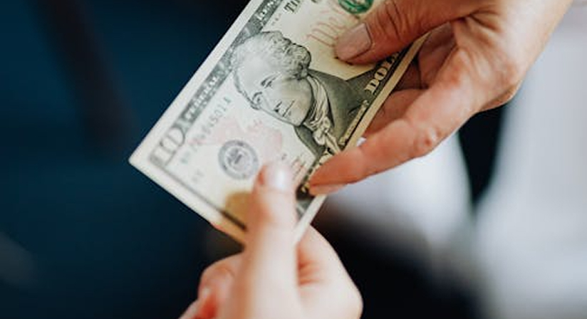 Hands exchanging a ten-dollar bill, symbolizing a financial transaction or payment process.