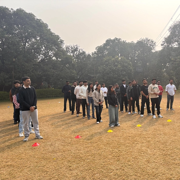 Group of young adults standing on a field with trees in the background under a cloudy sky.