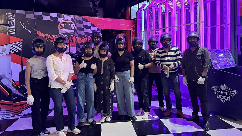 Group ready for go-kart racing with helmets and gloves in an indoor track setting.